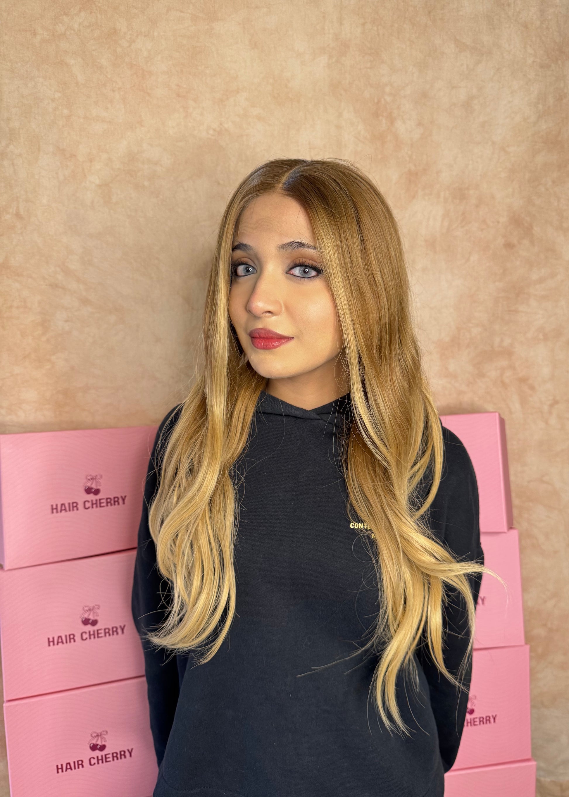 Woman wearing a 100% human hair caramel blonde wig with a realistic natural hairline, styled for a soft and effortless look.